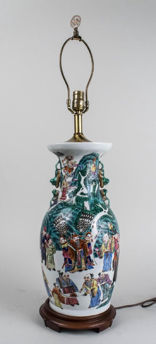 Chinese Porcelain Lamp: Vase form single light lamp decorated with figures and with foo lion handles. Base, height 19 1/2 inches. Notice to bidders: Condition reports and additional photographs are provided by request as a c