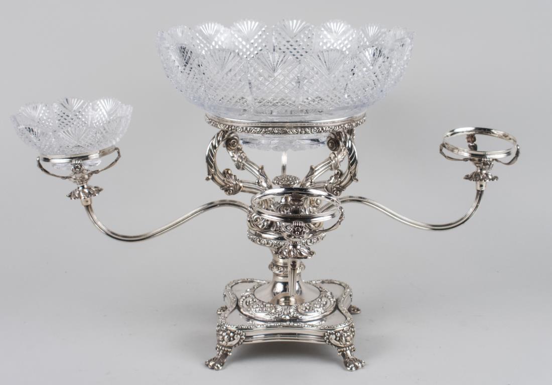Silver Plated Epergne: Four scrolled arms centering a cut glass bowl (two small bowls missing). Height 14 inches. Notice to bidders: Condition reports and additional photographs are provided by request as a courtesy to our 