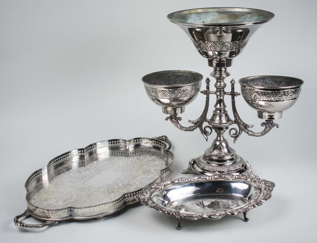 Three Silver Plated Table Articles: Two handle serving tray, an epergne and a bread tray. Epergne, height 16 1/2 inches. Notice to bidders: Condition reports and additional photographs are provided by request as a courtesy to our client