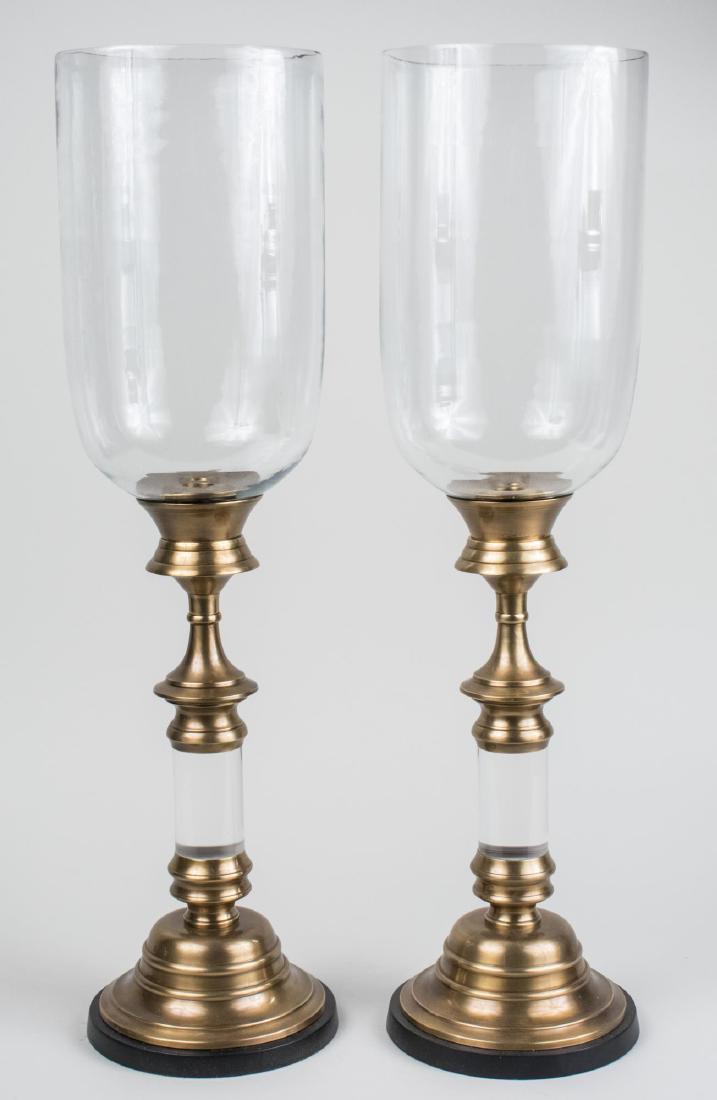 Pair of Candle Holders with Hurricane Shades: Cylindrical colorless glass shades on ring turned and knopped brass candlesticks. Height, 27 inches, diameter of base 8 1/2 inches. Notice to bidders: Condition reports and additional photographs are 