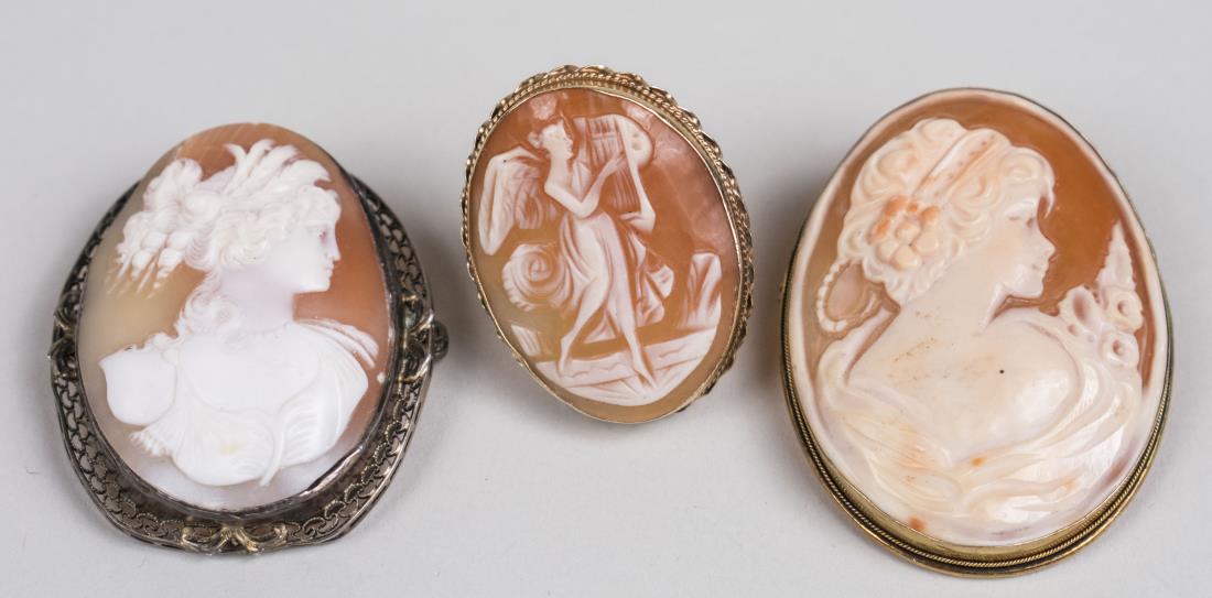 Two Italian Shell Cameos & Cameo Ring: One, late19th century, with silver filigree border, another 20th century, marked 800 and a 14k yellow gold ring set with a cameo depicting a muse. Size 9. Notice to bidders: Condition reports and addi