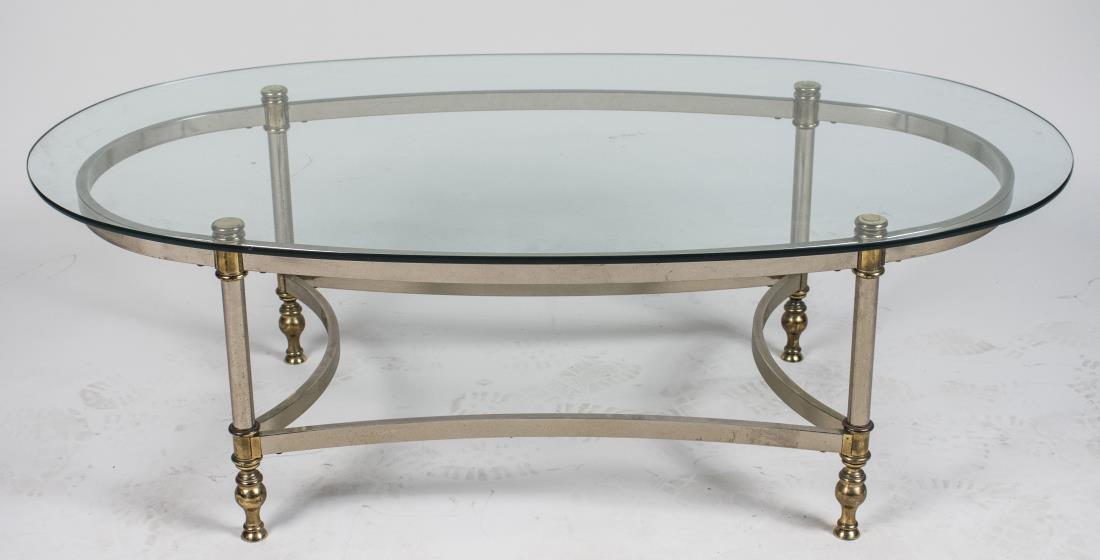 Glass Top Coffee Table: Oval glass top, brass and brushed steel frame with modified box stretcher. Height 16 inches, width 49 inches, depth 27 inches. Notice to bidders: Condition reports and additional photographs are provi