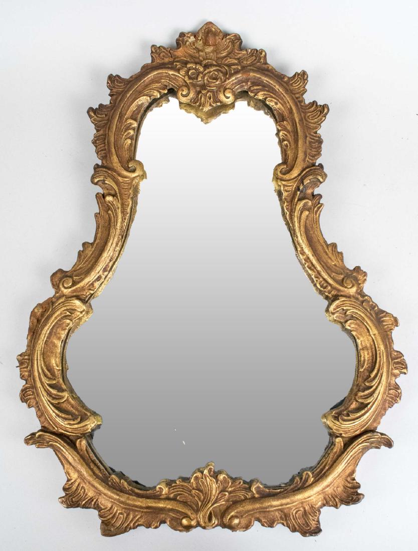 Rococo Style Gilt Wood Mirror: Cartouche shaped mirror with leafy scroll decoration. Height 24 inches, width 18 inches. Notice to bidders: Condition reports and additional photographs are provided by request as a courtesy to our cl