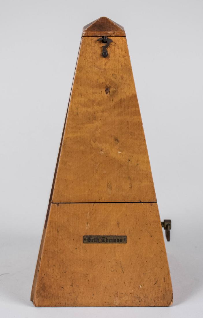 Seth Thomas Metronome: Of typical form. Height 8 3/4 inches. Notice to bidders: Condition reports and additional photographs are provided by request as a courtesy to our clients, as such any condition report is only an opin