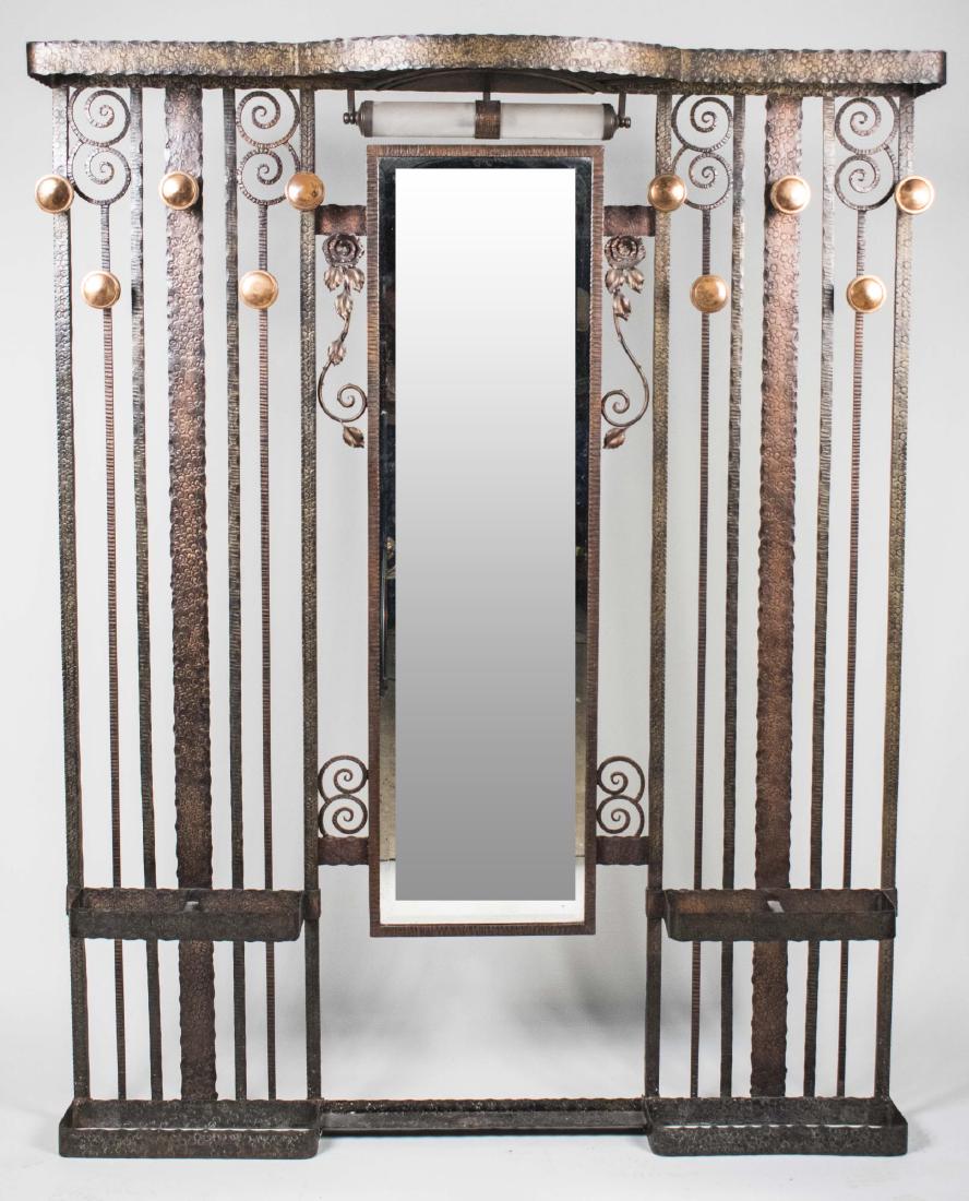 Iron and Brass Hall Stand: In the style of Edgar Brandt, upright supports with scroll tops, centering a mirror, brass hooks. Height 6 feet 3 inches, width 59 inches, depth 14 inches. Notice to bidders: Condition reports and add