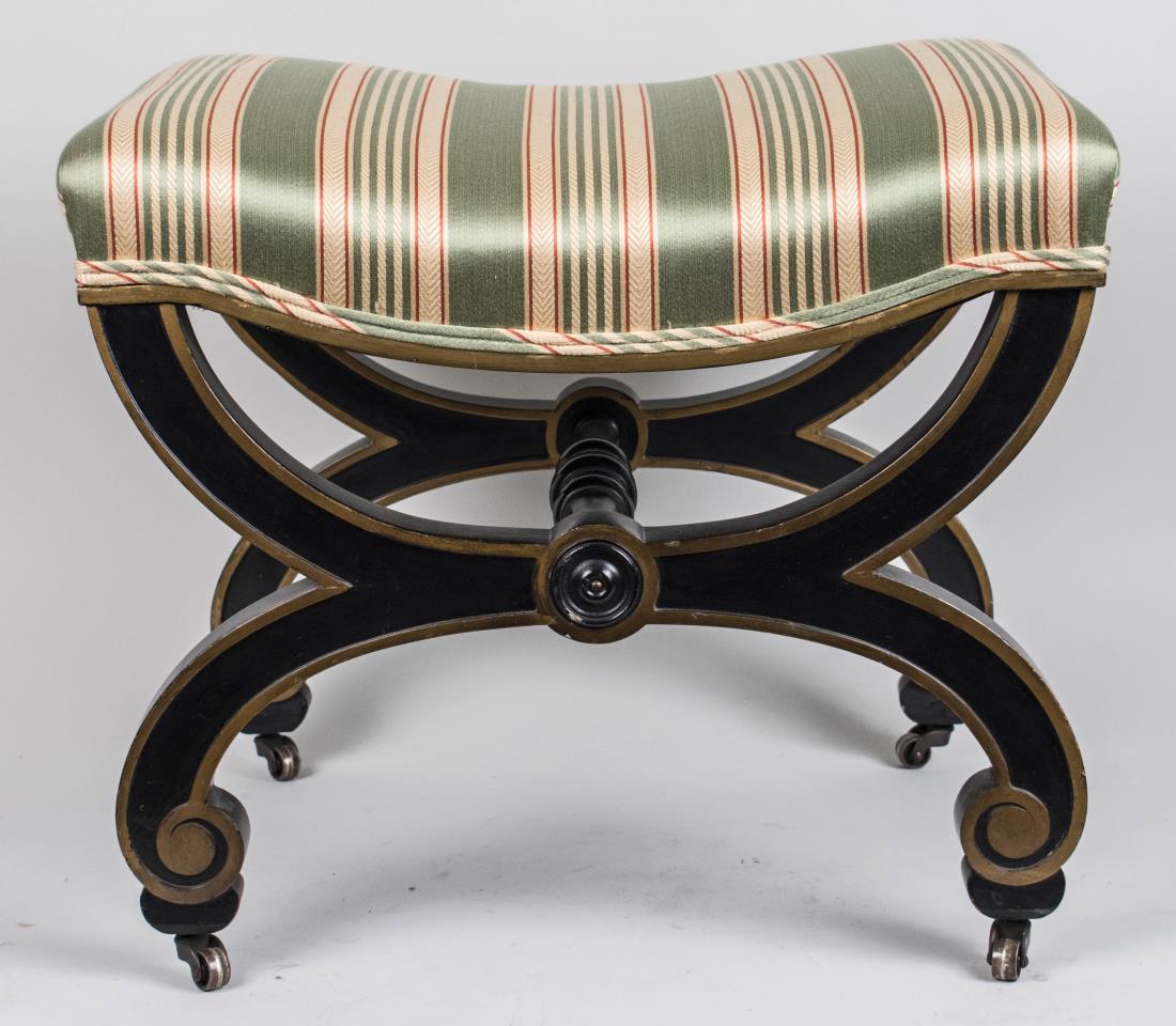 Parcel Gilt and Painted Curule Stool: Stripe upholstered seat, parcel gilt and black painted stool on casters. Height 17 inches, width 16 inches, depth 22 inches. Notice to bidders: Condition reports and additional photographs are provide