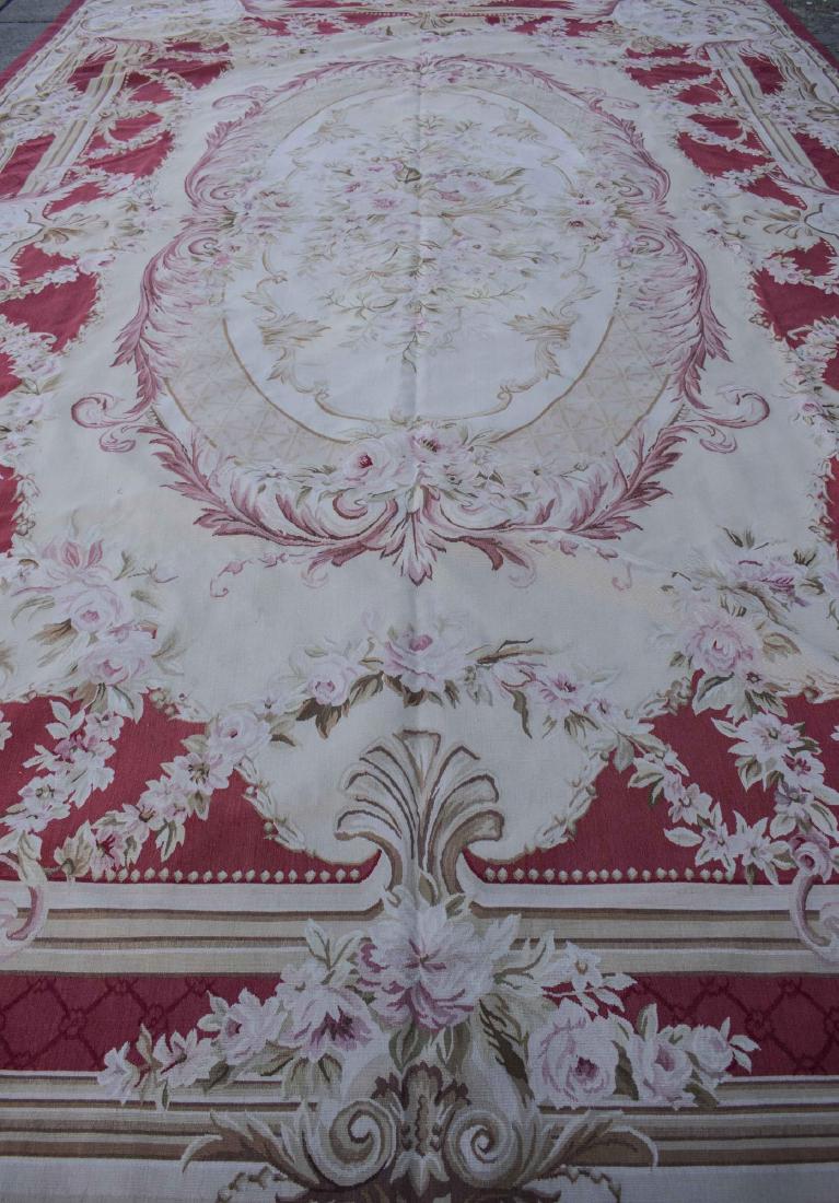 Sino-Aubusson Carpet: Central medallion on an ivory field with red spandrels, within a red and tan border, allover floral swag and scroll decoration. 18 feet x 11 feet 5 inches. Notice to bidders: Condition reports and add
