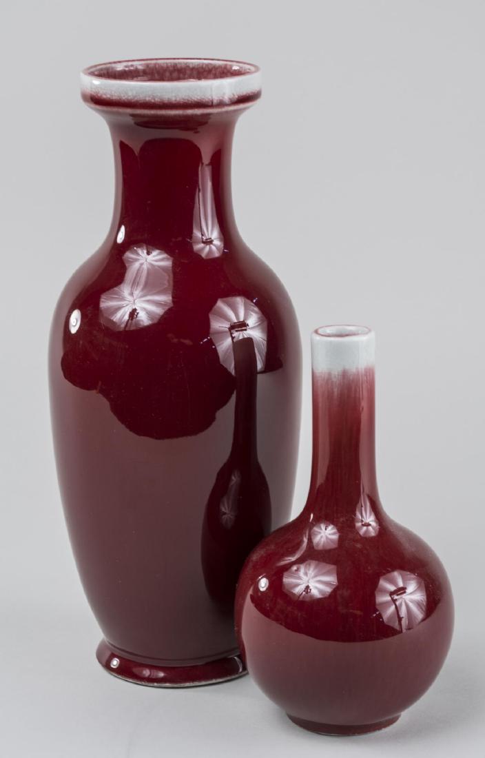 Two Chinese Sang de Beouf Vases: One, ring rim, waisted neck, ovoid body, the other, a bottle form vase. Taller, height 12 inches. Notice to bidders: Condition reports and additional photographs are provided by request as a courtesy 
