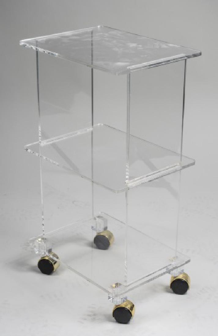 Lucite Television Stand: Three tiers, with rectangular top over two conforming open shelves, On casters. Height 28 1/2 inches, width 16 inches, depth 12 inches. Notice to bidders: Condition reports and additional photographs