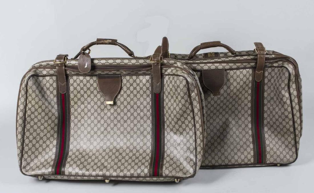 Two Gucci Suitcases: GG Supreme canvas with leather trim and nylon strap. Length 30 inches. Notice to bidders: Condition reports and additional photographs are provided by request as a courtesy to our clients, as such any