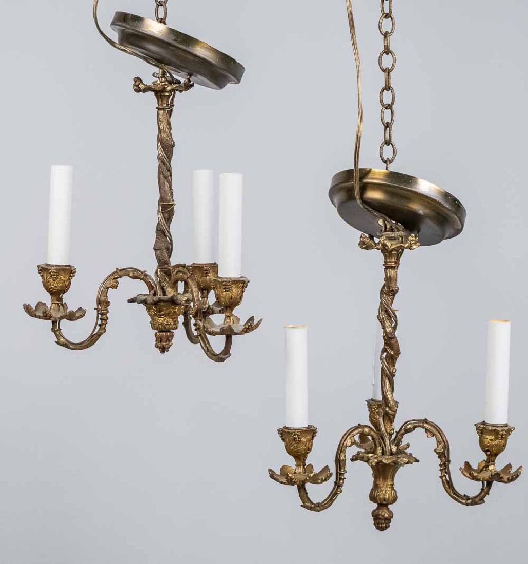Pair of Gilt Bronze Fixtures: Neoclassical style, each with three scrolled arms ending in urn form candle cups. Height 12 1/2 inches, width 12 inches. Notice to bidders: Condition reports and additional photographs are provided by