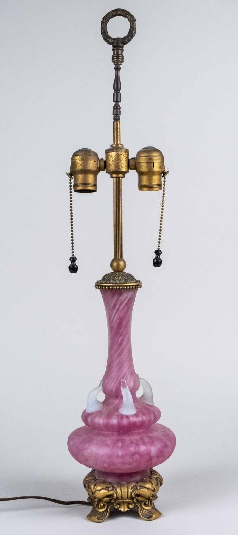 Bronze Mounted Art Glass Lamp: Pink satin glass two light lamp. Base, height 13 1/2 inches. Notice to bidders: Condition reports and additional photographs are provided by request as a courtesy to our clients, as such any condition