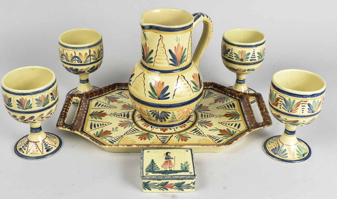 Quimper Table Set: Comprising a pitcher, four goblets, covered box and tray. Pitcher, height 9 3/4 inches. Notice to bidders: Condition reports and additional photographs are provided by request as a courtesy to our cli