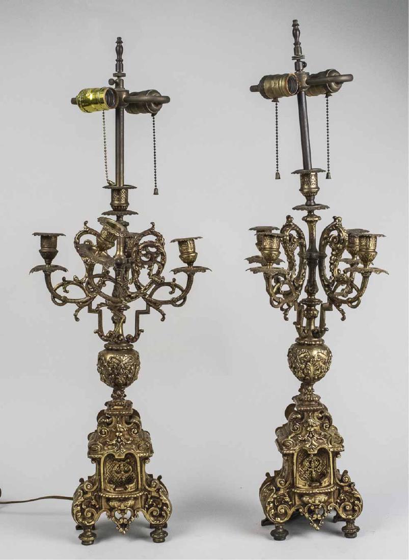 Pair of Brass Candelabra Lamps: Rococo style candelabra converted to two light lamps. Height overall 30 inches. Notice to bidders: Condition reports and additional photographs are provided by request as a courtesy to our clients, as