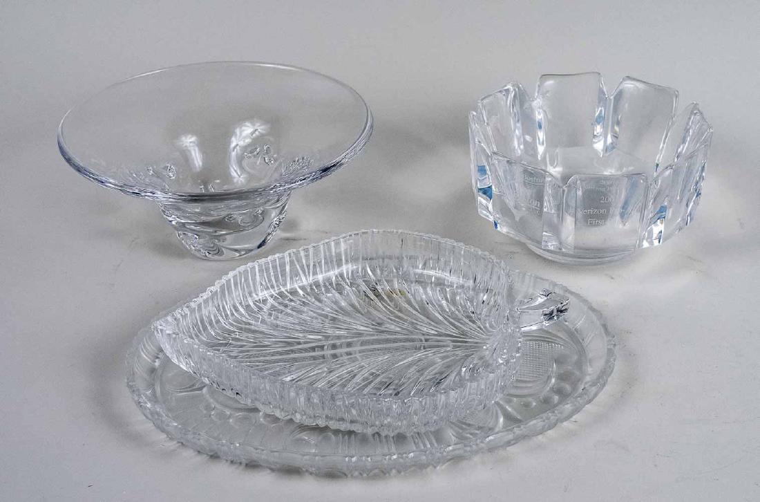 Four Colorless Glass Table Decorations: Two bowls and two trays. Steuben bowl, diameter 9 3/4 inches. Notice to bidders: Condition reports and additional photographs are provided by request as a courtesy to our clients, as such any conditio