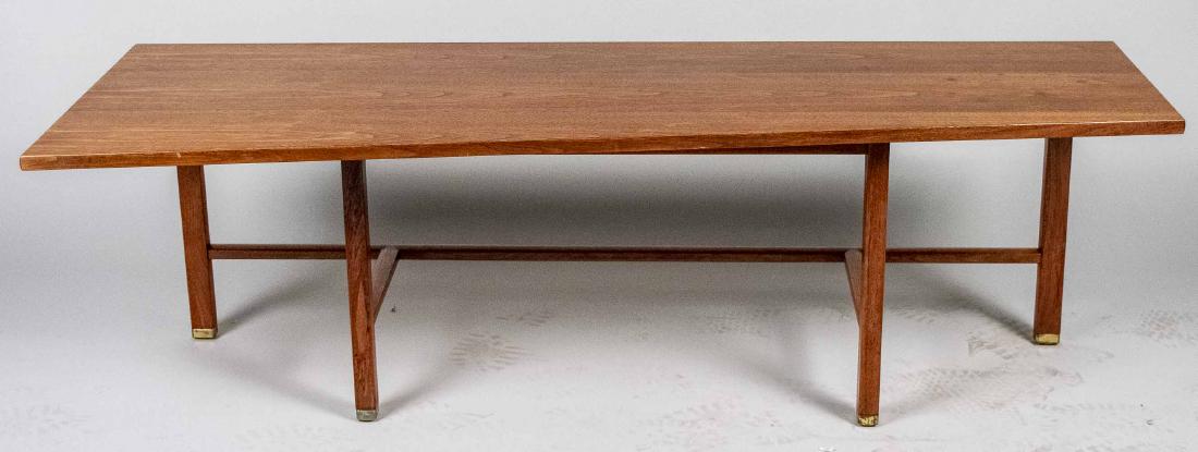 Edward Wormley for Dunbar Walnut Coffee Table: Trapezoidal top with stretcher and brass-capped feet, rectangular brass Dunbar tag underneath. Height 18 inches, width 60 inches, depth 22 inches. Notice to bidders: Condition reports and additional p
