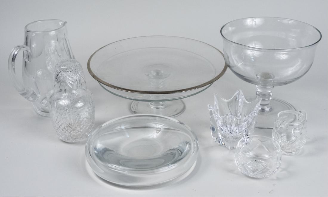 Group of Colorless Glass Table Articles: Nine pieces, including a Tiffany & Co. cake plate, a Baccarat pitcher, an Orrefors votive, etc. Pitcher, height 8 1/2 inches. Notice to bidders: Due to the nature of this particular online sale, the l