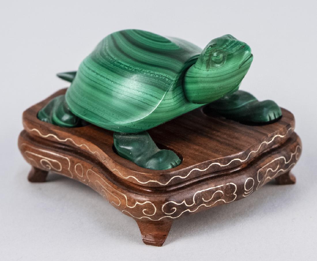 Malachite Tortoise: Carved with head raised, wood base. Tortoise, length 3 1/2 inches. Notice to bidders: Condition reports and additional photographs are provided by request as a courtesy to our clients, as such any con