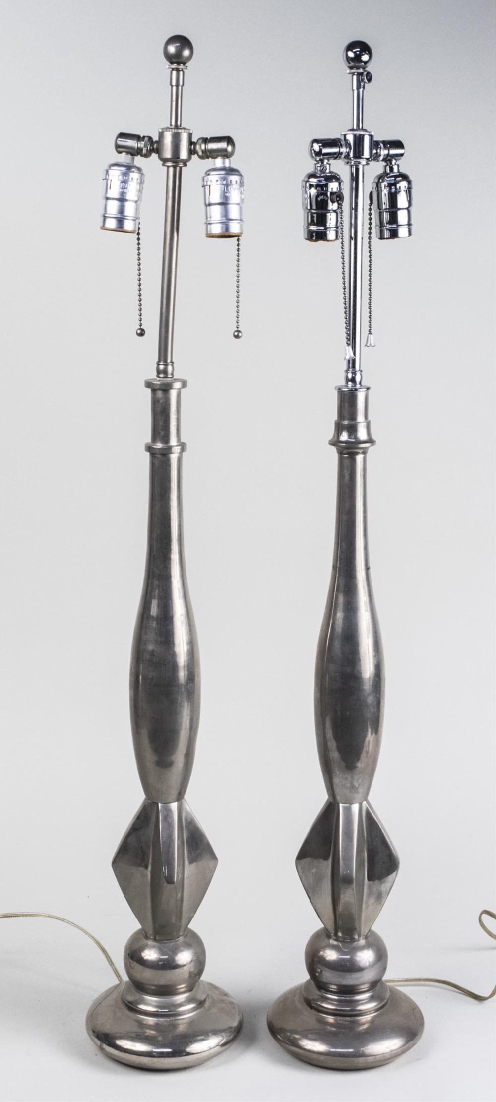 Pair of Chrome Lamps: Each a two light lamp on a narrow baluster above a flange decoration and circular base. Height overall 35 1/4 inches. Notice to bidders: Due to the nature of this particular online sale, the lots offe