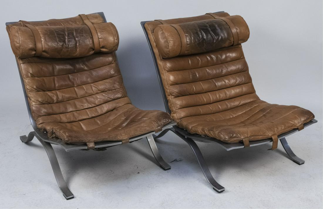 Pair Arne Norell Ari Lounge Chairs: Swedish tan leather and steel lounge chairs. Height 30 inches, width 26 inches, depth 40 inches. Notice to bidders: Condition reports and additional photographs are provided by request as a courtesy t
