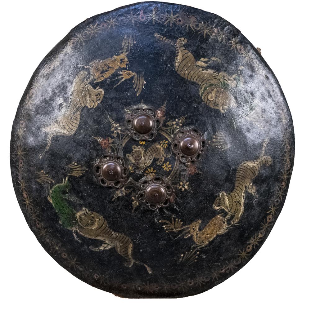 Indo-Persian Leather Dhal Buckler: Polychrome painted with scenes of tigers catching prey. Approximate diameter 19 inches. Notice to bidders: Condition reports and additional photographs are provided by request as a courtesy to our cli