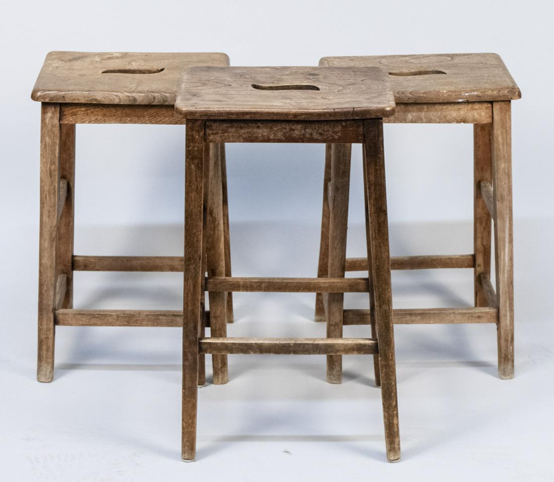 Three Vintage Stools: Each with panel seat with open carrying handle, with legs joined by box stretcher. Largest, height 26 inches, width 15 inches, depth 11 inches. Notice to bidders: Condition reports and additional phot