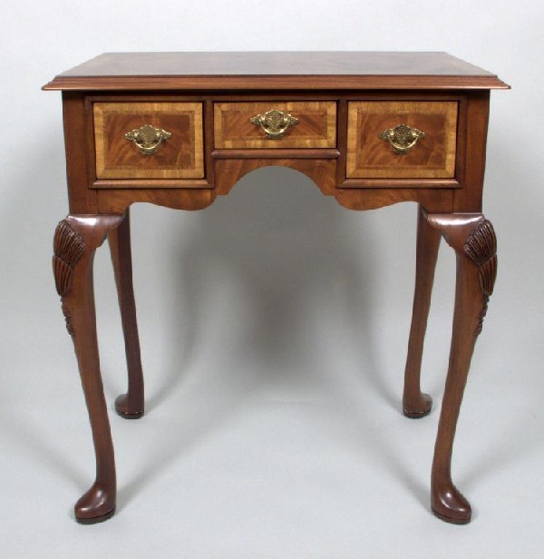 George III Style Mahogany Lowboy: Hickory Chair Co. Rectangular top with crossbanded edge above three drawers, cabriole legs with carved knees ending on slipper feet. Height 29 inches, width 26 inches, depth 16 3/4 inches.