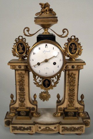Louis XVI Style Gilt Metal and Marble Clock: Gilt metal mounted white marble clock with an enamel dial signed Guy d'amour a Paris and with Apollo mask pendulum, surmounted by a fruit filled urn and flanked by two leaf decorated columns with gilt