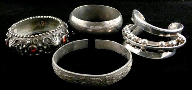Four Bracelets: Sterling silver and silvered metal, comprising a sterling silver bangle, a silver cuff with sliding bead decoration, a middle eastern metal jewelled bangle and an Asian metal bangle with raised dragon