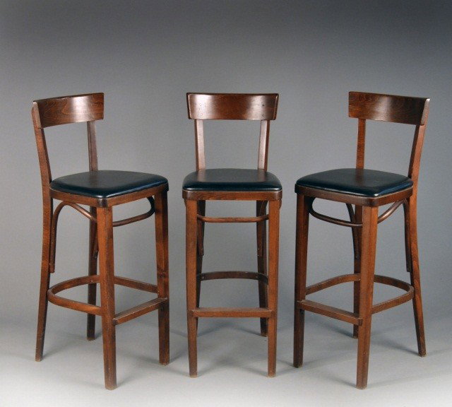 Three Fruitwood Bar Stools: Tablet crest rail on square side rails, black leather upholstered seat on square legs joined by box stretcher. Height 42 inches, width 15 inches, depth 17 inches. Note: Removed From The Steinway Mansi