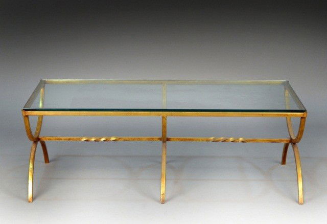 Contemporary Glass Top Coffee Table: Rectangular glass top on a gilt metal base with three curule legs. Height 16 3/4 inches, width 48 inches, depth 24 inches.