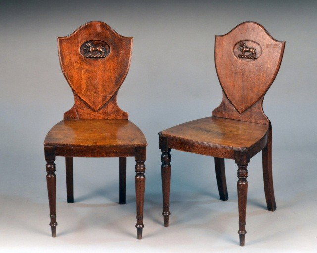 Pair of English Mahogany Hall Chairs: Early 19th century, shield form backs, carved seats and turned legs. Height 35 inches, width 16 inches, depth 1/2 20 inches.