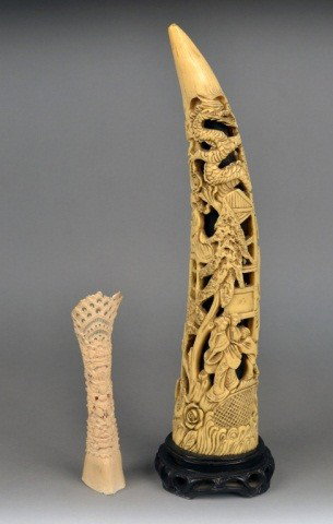 Two Asian Carved Tusk Decorations: One a simulated ivory Asian scene with dragons and figures and the other a carved ivory Asian deity. Taller 19 1/2 inches. (As is condition)