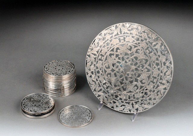 Webster Sterling Silver Coaster and Trivet Set: Comprising a silver mounted circular trivet and twenty silver mounted coasters and a stand. Trivet diameter 8 inches.