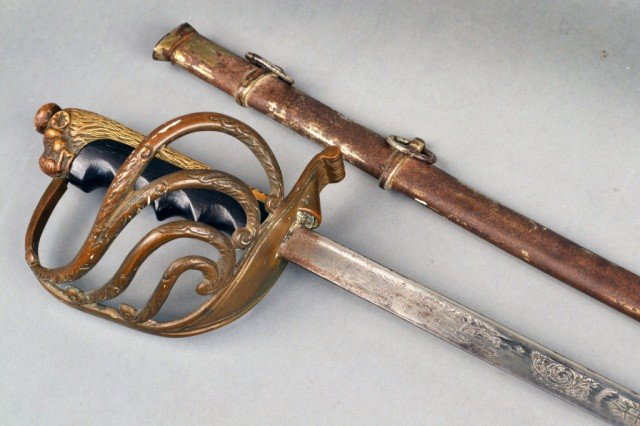 Antique Italian Naval Sword: Featuring a bronze basket hilt with the Italian improved handle design, a brass and ebonized wood grip in the form of a lion and a steel scabbard. Length with scabbard 41 inches.
