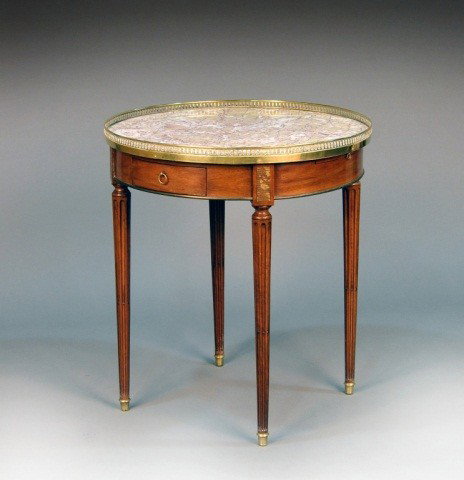 Louis XVI Style Mahogany Bouillotte Table: Marble top with brass gallery, above two small drawers and two leather inset brushing slides, on tapered stop fluted legs. Height 28 1/2 inches, diameter 25 3/4 inches.