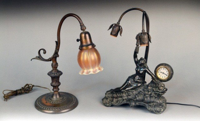 Two Victorian Style Table Lamps: Both patinated metal lamps with scroll arms ending in glass floriform shades including one with figural decoration and a clock. Lamp with clock, height 17 inches.