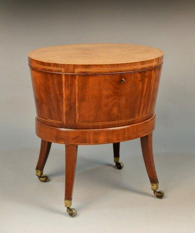 Victorian Mahogany Cellarette: Oval, with banded inlaid top, on square slightly splayed legs ending in brass casters, fitted interior. Height 25 3/4 inches, width 24 1/2 inches, depth 19 1/4 inches.