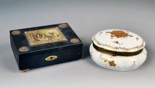 Two Dresser Boxes: One an oval porcelain box with gilt floral decoration, and the other, a musical box with silk panel inset in the top. Oval box, height 3 3/4 inches, width 7 inches, depth 6 inches.