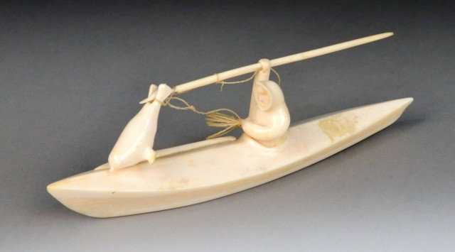 Lewis Iyakitan (20th c.) Whalebone Carving: Depicting a man harpooning a seal from a canoe, signed on the bottom. Length 9 inches.