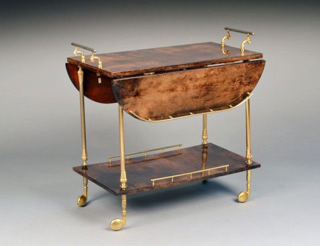 Brass and Exotic Wood Two Tier Cart: Rectangular top having D shaped drop leaves with brass galleries, on brass columnar supports joined by a conforming lower shelf, brass casters. Height 29 3/4 inches, width 32 inches, depth 18 inches.