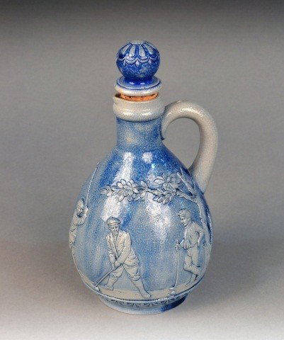 Mettlach Wine Pitcher: Early 20th century, decorated with a scene of men playing golf. Height 9 inches.