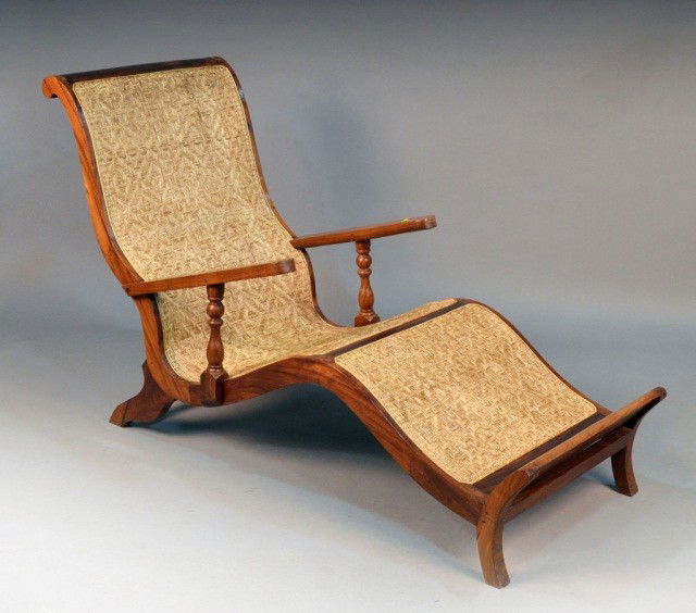 Anglo Indian Colonial Wicker Chaise: Flattened armrests, wicker seat, atop four splayed legs. Height 37 1/2 inches, width 25 inches, depth 58 inches.