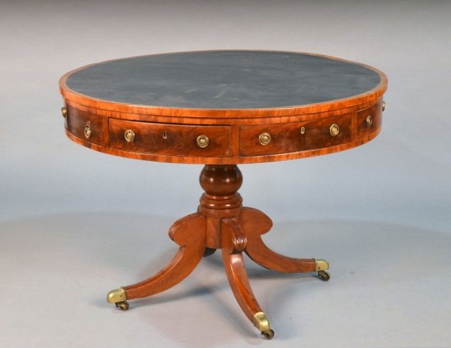 George III Style Mahogany Drum Table: 19th century, circular with simulated leather top over conforming drawers, quatrepartite base with brass casters. Height 30 inches, diameter 41 1/2 inches.