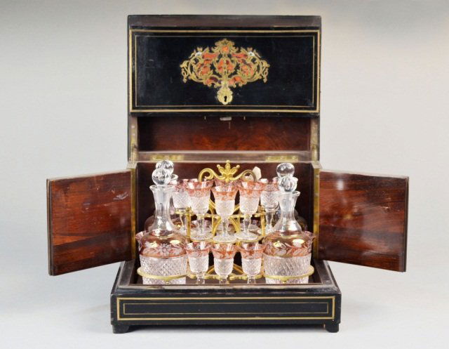 French Cave a Liqueur: Brass inlaid ebonized wood case with hinged lid and front panel, opening to four flashed glass decanters and fourteen cordial glasses. Height 10 1/4 inches, width 12 3/4 inches, depth 10 inches.