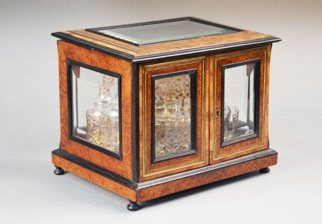 French Cave a Liqueur: Burl and rosewood case with beveled glass inset hinged top and front panels opening to four gilt decorated glass decanters and sixteen cordial glasses, bun feet. Height 11 1/2 inches, width 13 3/4 inc