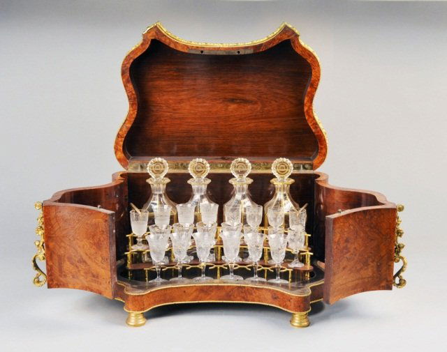 French Cave a Liqueur: Inlaid burl wood gilt metal mounted case with hinged top and front panels, opening to four gilt decorated glass decanters and twenty-two cordial glasses. Height 11 1/2 inches, width 18 inches, depth 1