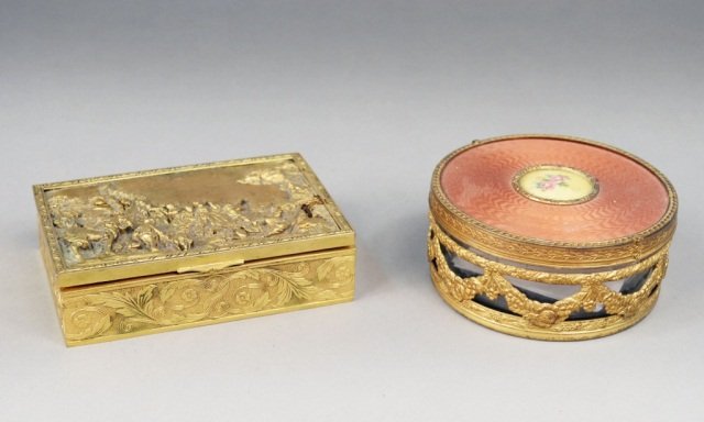 Two Gilt Metal Boxes: One, a French circular dresser box with floral decoration, together with a brass humidor decorated with a raised scene of figures in a landscape. Dresser box, height 2 inches, diameter 4 1/2 inches.