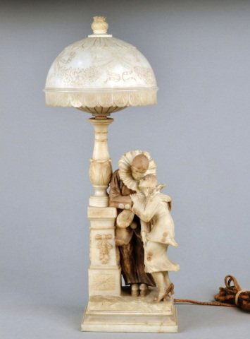 Alabaster Figural Lamp: Modeled with a pair of jesters in an amorous embrace, with an alabaster dome shaped shade. Height 29 inches.