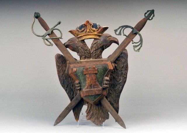 Wood and Metal Coat of Arms: Wood carved and polychrome decorated, with two metal crossed swords. Height 28 inches.